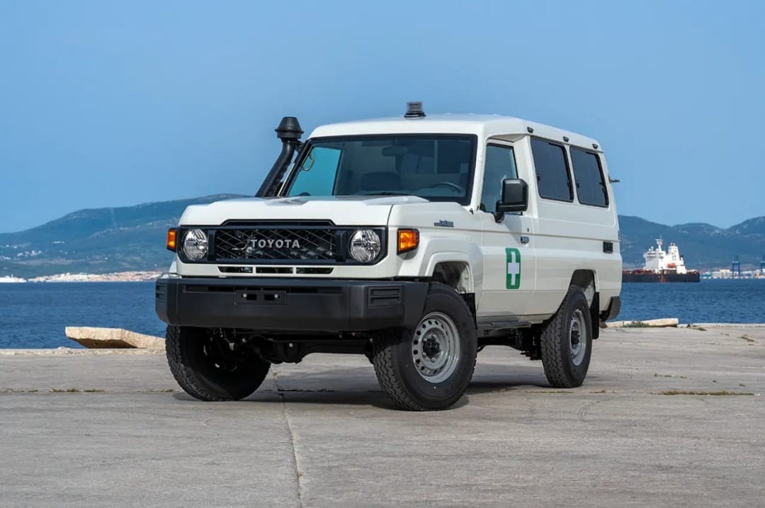 A white Land Cruiser parked by the water